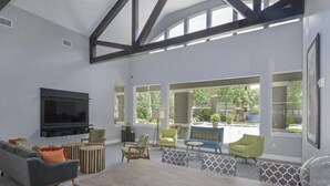 Amplia sala de estar con una gran mesa de madera, asientos cómodos, un televisor de pantalla plana y ventanas amplias con vistas al exterior.