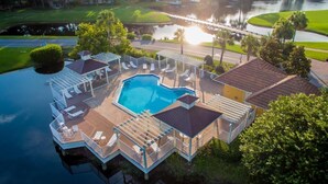 A pool area with a large rectangular pool, multiple lounge chairs, and a covered deck.