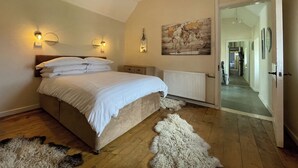 A bedroom with a large bed, two wall-mounted lights, a world map, a radiator, and a fluffy rug. - 3 bedroom accommodation in Corran, near Arnisdale (Corran, near Arnisdale)
