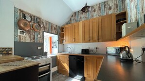 A kitchen with wooden cabinets, a stove, a dishwasher, and a kettle. - 3 bedroom accommodation in Corran, near Arnisdale (Corran, near Arnisdale)