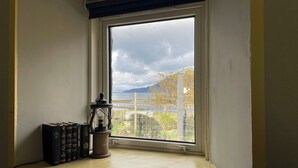 A window with a view of a body of water, mountains, and a wire fence. - 3 bedroom accommodation in Corran, near Arnisdale (Corran, near Arnisdale)