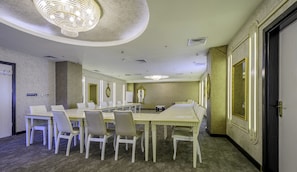A conference room with a long table, white chairs, a chandelier, and ornate wall decorations. - Real House Boutique Hotel (Kocasinan)
