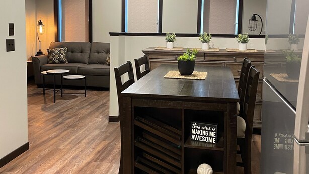 A modern kitchen with a dining area, wooden flooring, and a built-in bench with storage. - NEW, NEW, NEW! Wabasha Downtown Studio 113 Pembroke Ave. #103 (Wabasha)