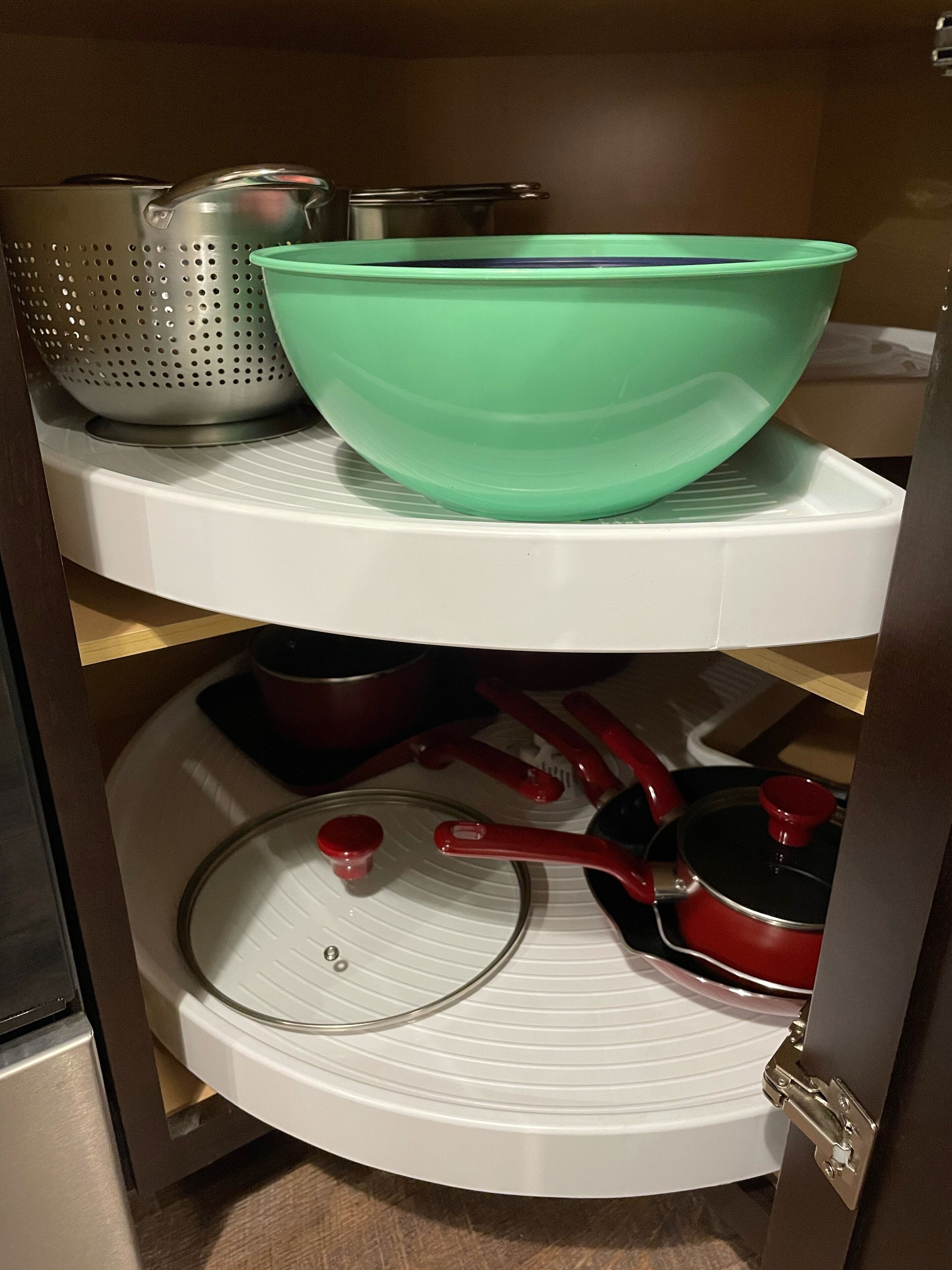 Una cocina con un bol verde en el estante superior y varias ollas y sartenes en el inferior.