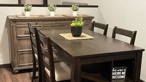 A dining area with a wooden table, four chairs, and a decorative shelf with a sign. - NEW, NEW, NEW! Wabasha Downtown Studio 113 Pembroke Ave. #103 (Wabasha)