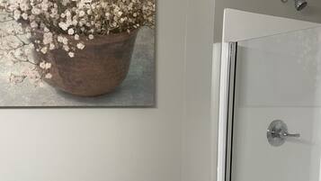 Un baño con ducha, inodoro y un cuadro de flores en la pared.