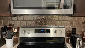 A kitchen with a stainless steel microwave, a black stove, and a toaster. - NEW, NEW, NEW! Wabasha Downtown Studio 113 Pembroke Ave. #103 (Wabasha)