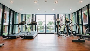 Uma academia com esteiras, elípticos e uma piscina, tudo visível através de grandes janelas.