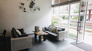 Uma sala de estar moderna com um sofá, duas poltronas, uma mesa de centro e um detalhe decorativo na parede em metal.