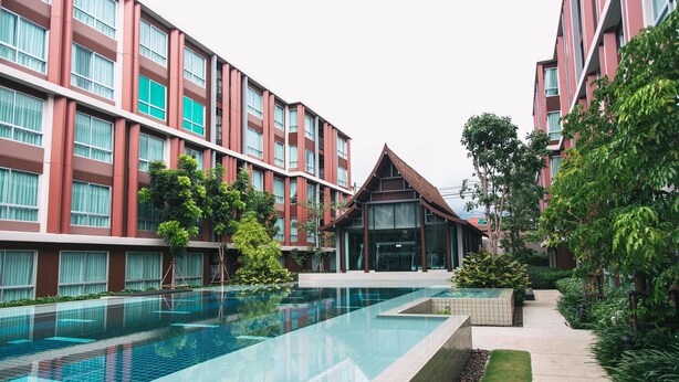 Hotel moderno com piscina, vários andares e fachada em tons de vermelho e branco.