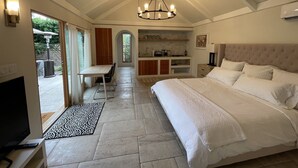 A bedroom with a large bed, a TV, and a kitchenette. - Charming, Private, Poolside Cottage (Glendale)