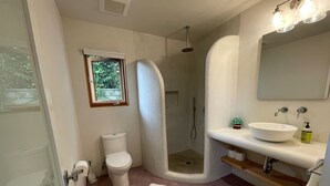 A bathroom with a toilet, a shower, a sink with a mirror, and a window. - Charming, Private, Poolside Cottage (Glendale)