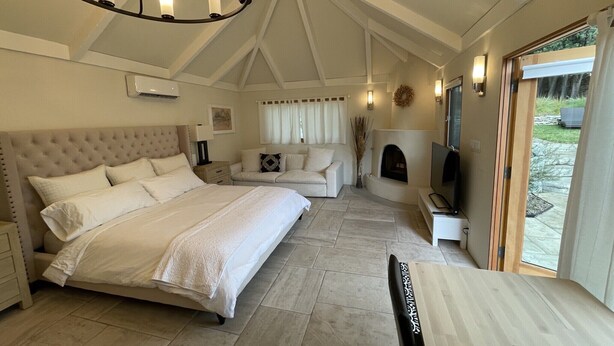 A bedroom with a large bed, a sofa, a TV, and a fireplace. - Charming, Private, Poolside Cottage (Glendale)