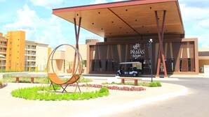 A modern building with a covered entrance, a golf cart, and a unique circular seating area. - Praias do Lago Eco Resort by WAM Experience (Caldas Novas)