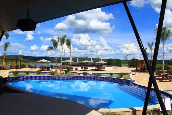 Relax by the pool surrounded by lush hills and a serene landscape.