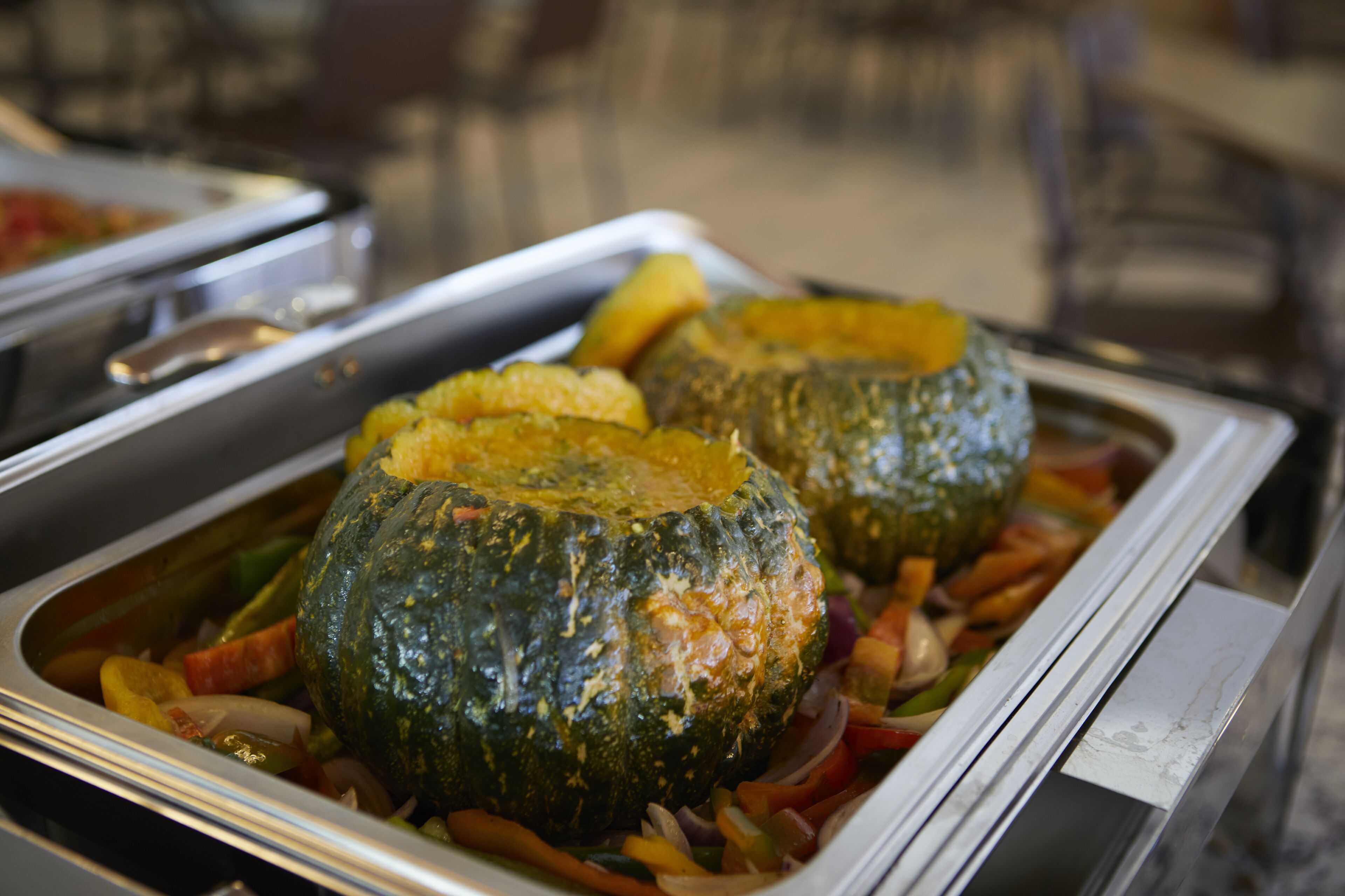 A buffet with roasted vegetables and a large squash.