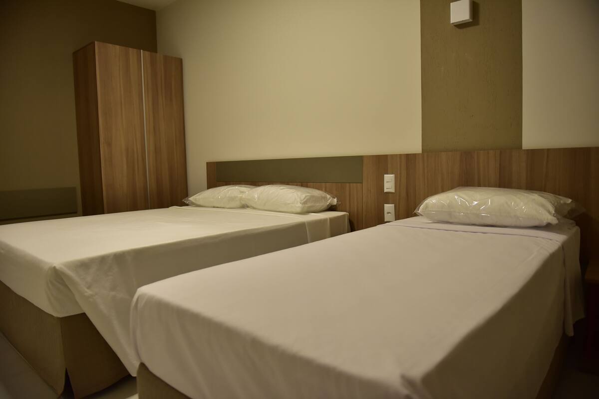 Two single beds with white linens in a hotel room.