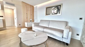 A modern living room with a sofa, a small round table, and a wall-mounted artwork.