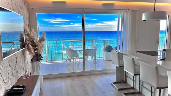 A modern room with a large sliding glass door leading to a balcony with a view of the sea.