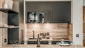 A modern kitchen with a central island, dark cabinets, and a hanging light fixture.