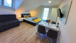 Un dormitorio con cama, mesitas de noche, un escritorio y sillas, una ventana y un espejo.