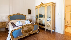 Una habitación con una cama grande y decorada, un aparador a juego y un mueble espejo.