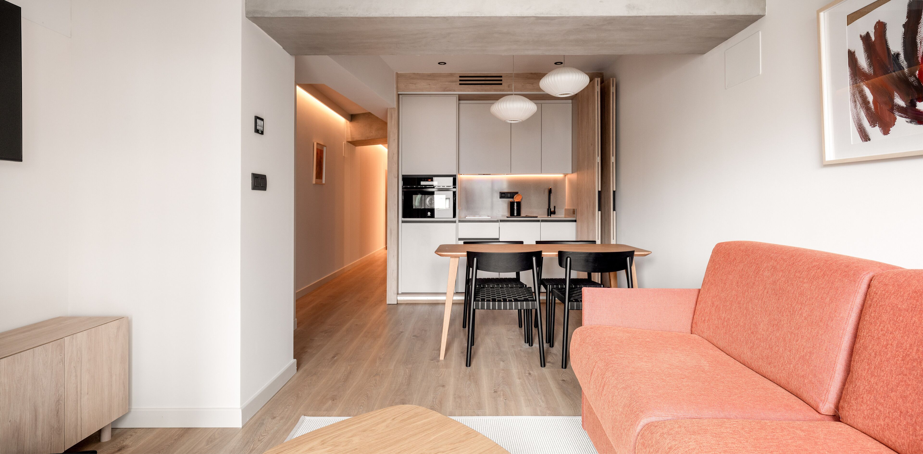Un soggiorno moderno con un divano, un tavolo da pranzo con sedie e una zona cucina con elettrodomestici.