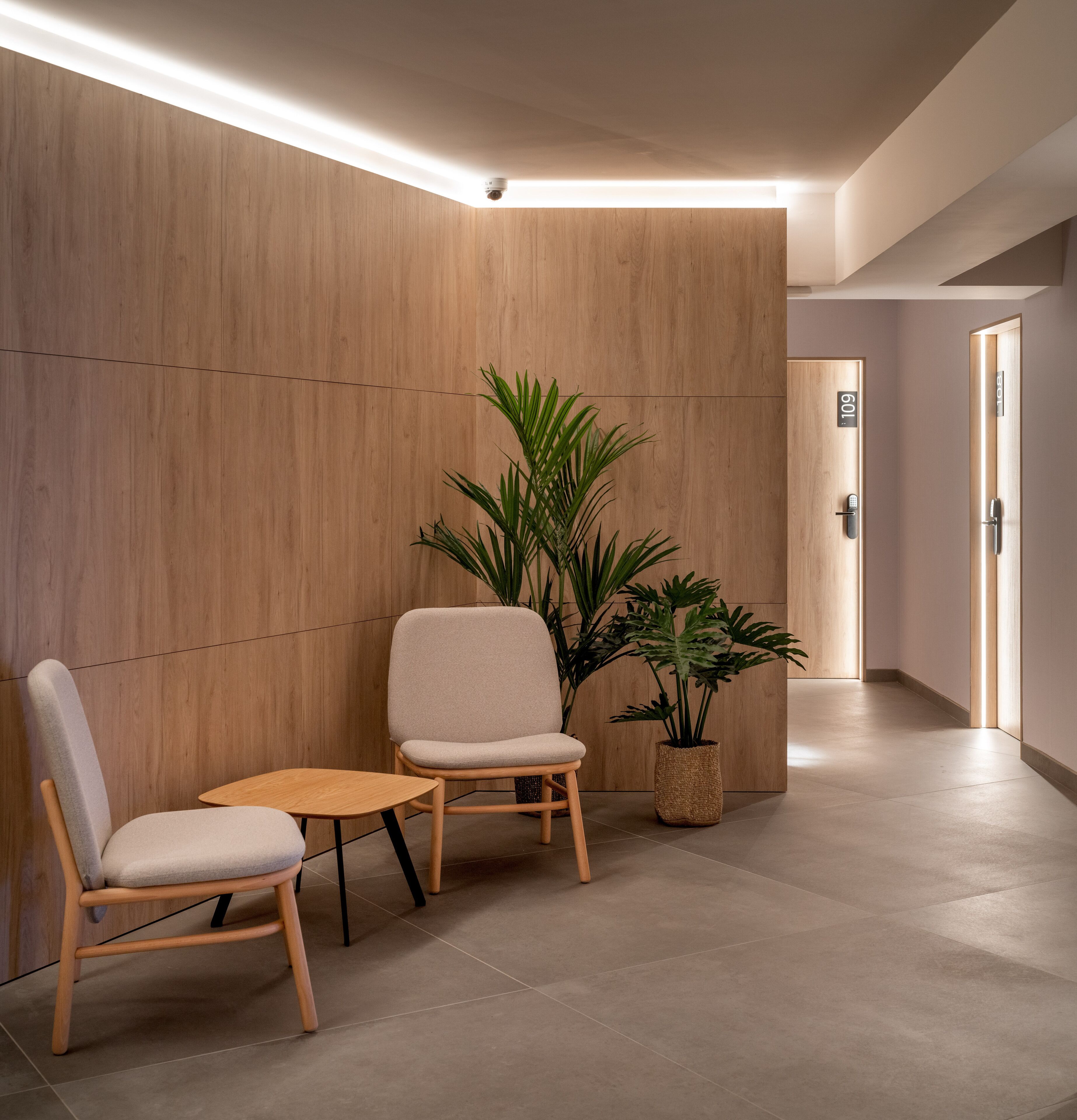 Un espace d’attente moderne comprenant deux chaises, une petite table et une plante en pot.