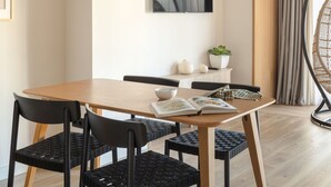 Un espace repas moderne avec une table en bois, des chaises noires et un luminaire suspendu.
