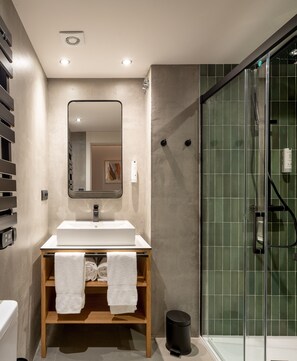 A modern bathroom with a large mirror, a white sink, and a glass shower enclosure.