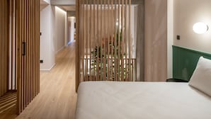 Une chambre d’hôtel moderne avec une cloison en bois, un lit et une vue sur un couloir.