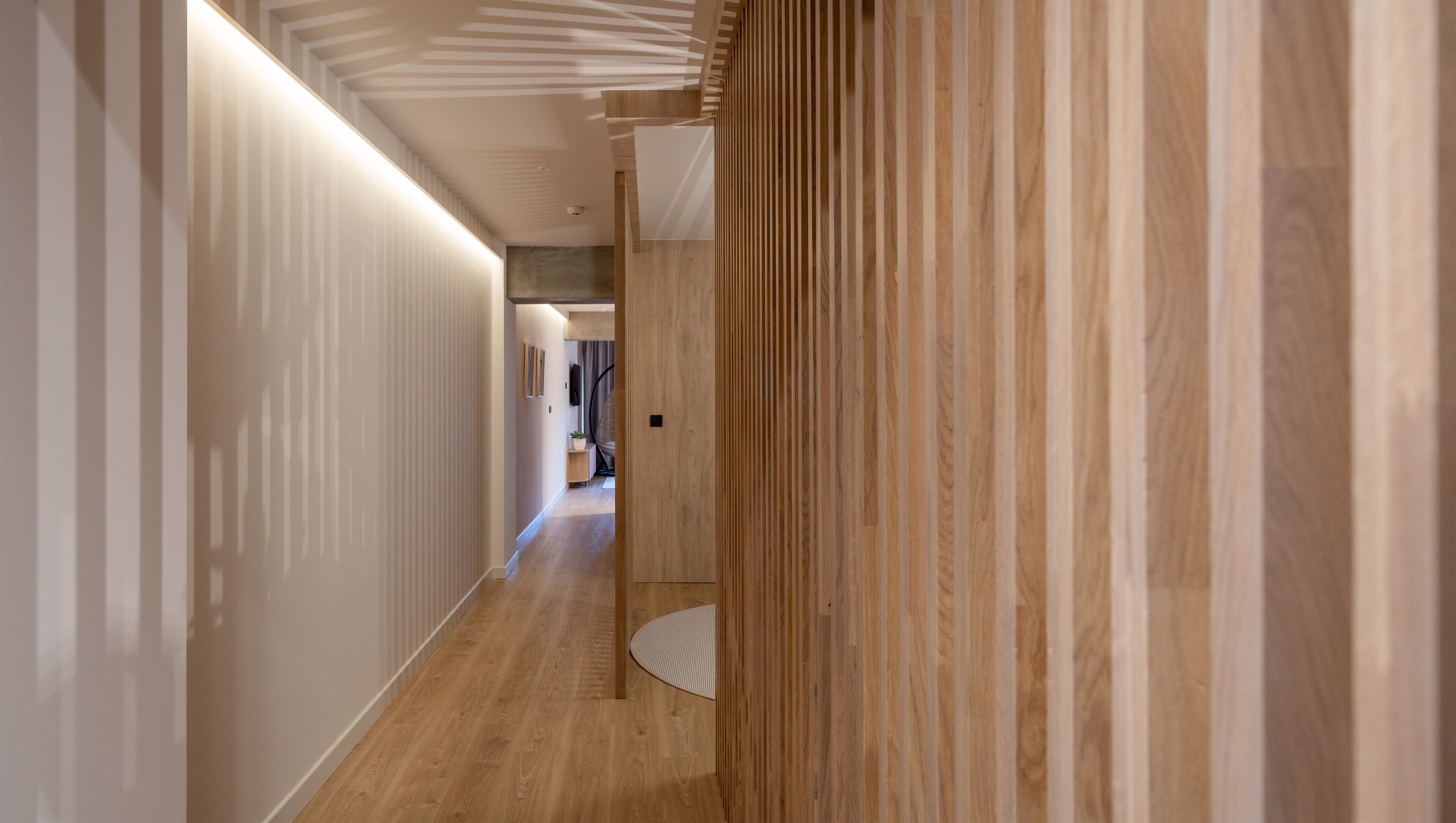 Un pasillo moderno con suelo de madera y un diseño de pared a rayas.