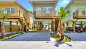 A row of beachfront bungalows with wooden balconies and a central walkway.