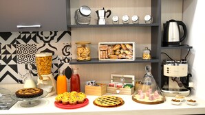 En morgenmadsbuffet med forskellige bagværk, en kaffemaskine og en juiceautomat.