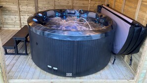 A hot tub with a control panel, a bench, and a towel rack inside a wooden cabin. - 3 bedroom accommodation in Stalmine, near Poulton-le-Fylde (Stalmine, near Poulton-le-Fylde)