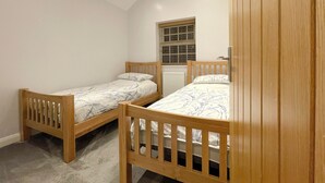 A bedroom with two wooden beds, a window with blinds, and a radiator. - 3 bedroom accommodation in Stalmine, near Poulton-le-Fylde (Stalmine, near Poulton-le-Fylde)