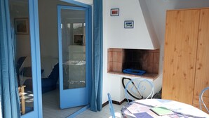 Une pièce comprenant un lit, une table recouverte d’une courtepointe, une armoire en bois et une petite cheminée.
