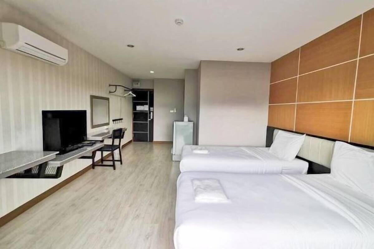 A hotel room with a TV, a desk, two beds, and a wardrobe.