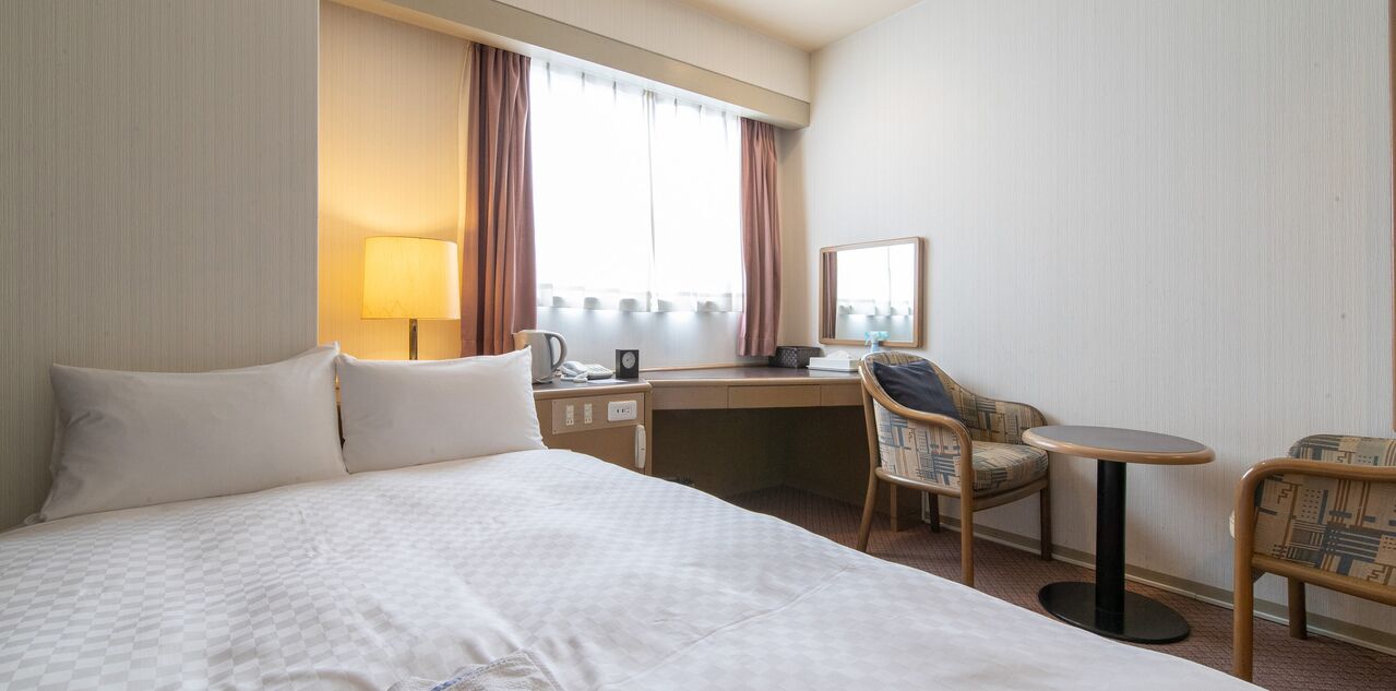 Ein Hotelzimmer mit Bett, Schreibtisch, Stuhl und einem kleinen Tisch.