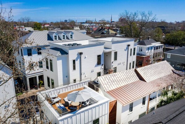 A residential area with modern houses, including a house with a rooftop deck and outdoor seating.