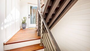 A narrow hallway with wooden flooring and a metal railing.