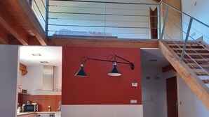 A spacious loft with a high ceiling, exposed wooden beams, a mezzanine level, and a kitchen area with modern appliances. - RURAL HOUSE AINGERU NATURE AND MOUNTAIN (Aránzazu)