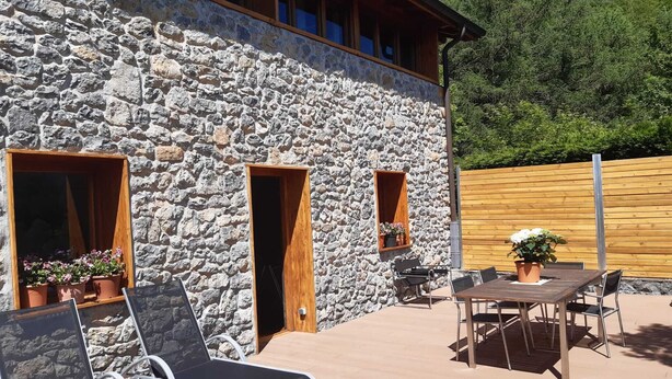 A stone building with a wooden deck, outdoor seating, and potted plants. - RURAL HOUSE AINGERU NATURE AND MOUNTAIN (Aránzazu)