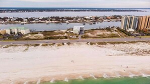 Luchtbeeld van een kustgebied met een strand, een jachthaven en woongebouwen.