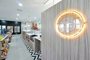 Un interior moderno con una zona de recepción que incluye un letrero circular iluminado y una máquina expendedora.