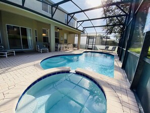 En swimmingpool med glasafskærmning, liggestole og en terrasse.