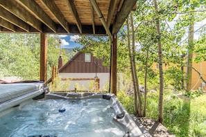 A hot tub under a wooden pergola with a view of a house and trees. - 57 Rasor Court by Summit County Mountain Retreats (Keystone)