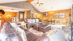 A log cabin interior with a leather sofa, wooden dining table, and a ceiling fan. - 57 Rasor Court by Summit County Mountain Retreats (Keystone)