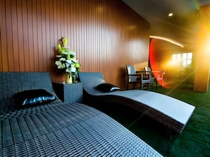 A modern hotel room with a curved bed, a small table, and a chair.