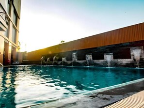 A swimming pool with a wooden deck and a stone wall.
